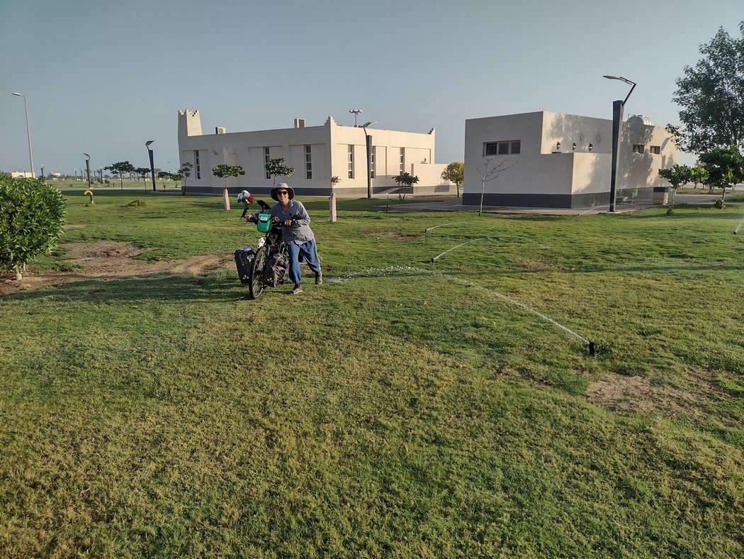 Julia schiebt Fahrrad über frisch gesprengten Rasen