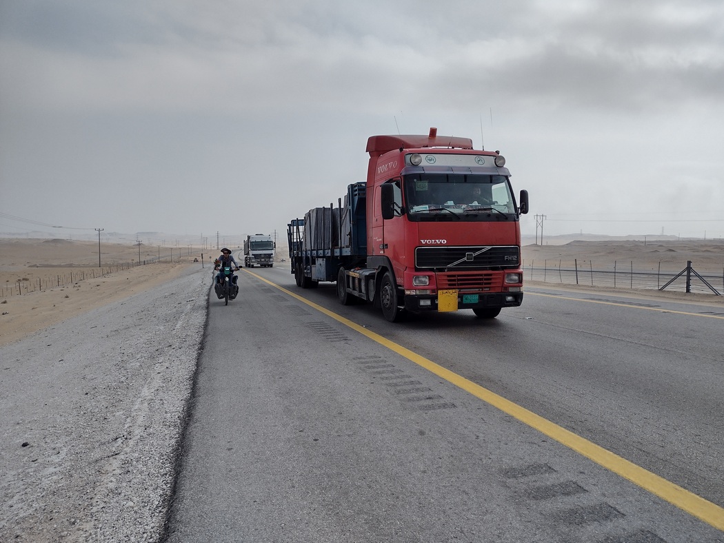Fahrrad auf dem Randstreifen, auf der Fahrbahn LKWs