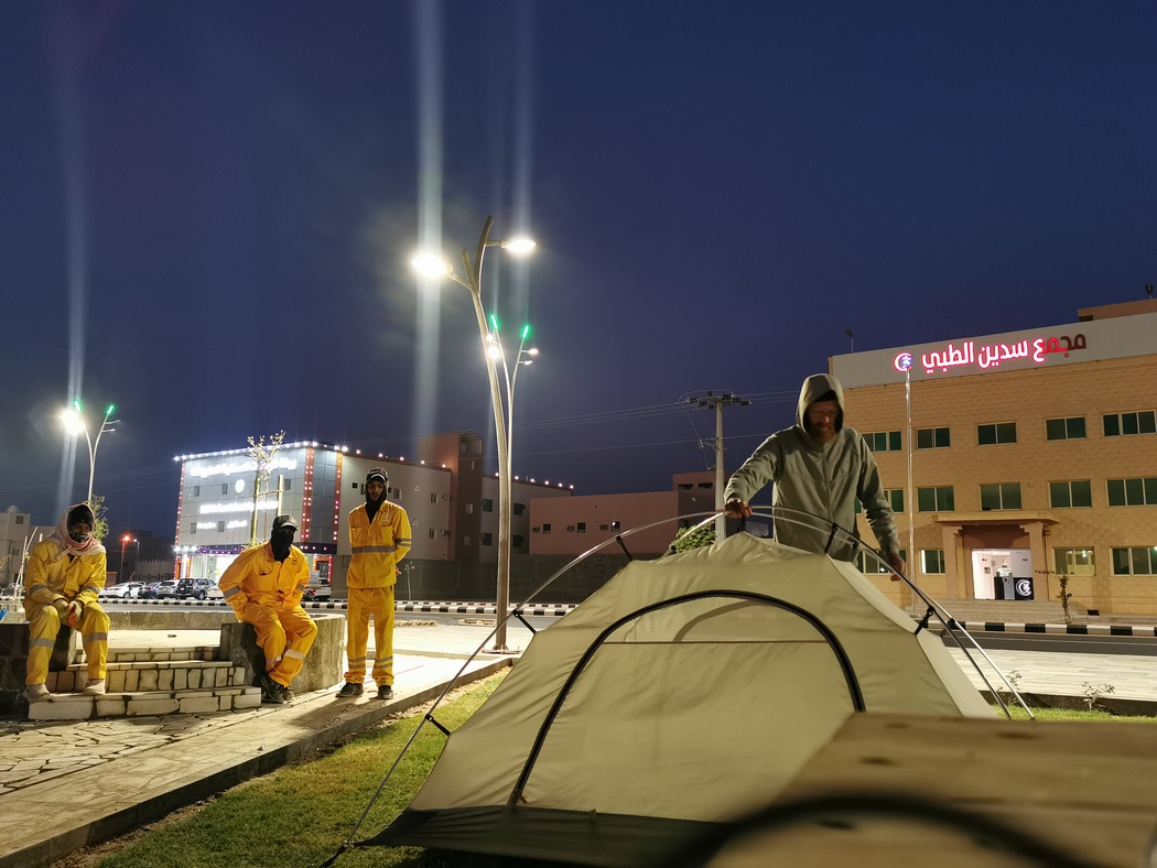 Während Tilmann das Zelt abbaut, schauen drei Bauarbeiter zu