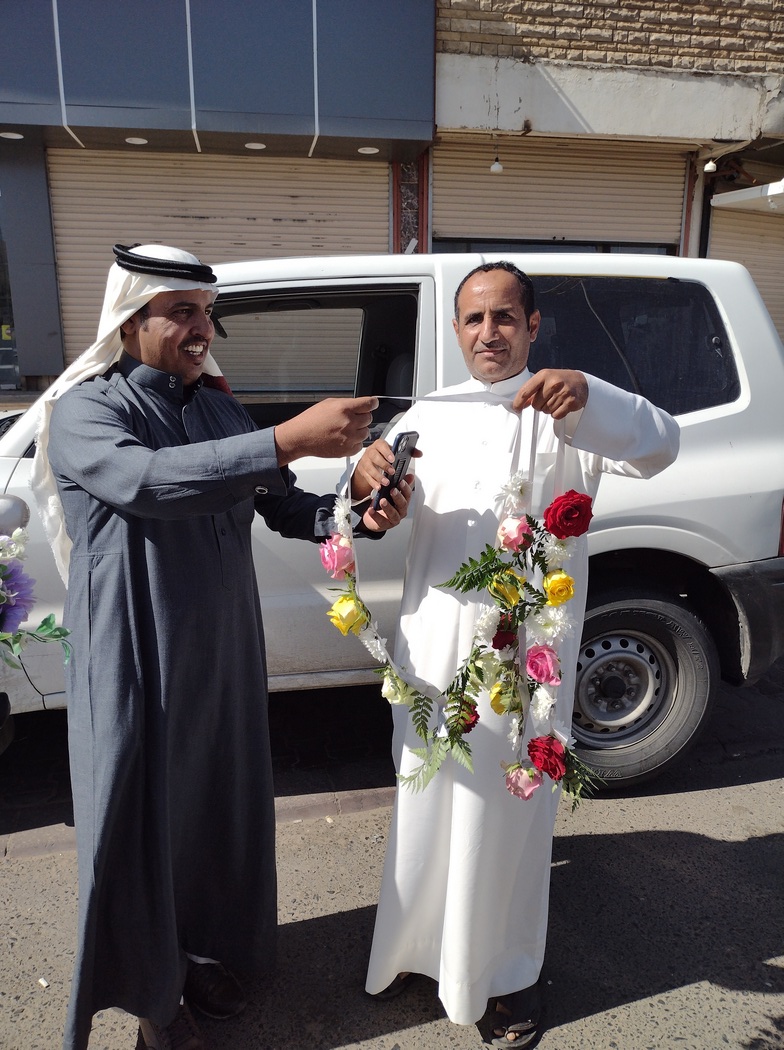 Zwei Männer überreichen uns Blumenkränze